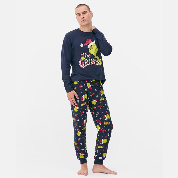 Person wearing navy Grinch Christmas pyjama set with long-sleeved top and matching patterned bottoms.