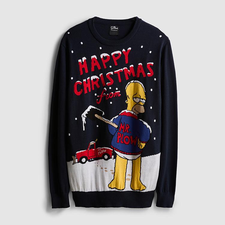 Person wearing beige sweatshirt over striped shirt with dark jeans, holding a black shoulder bag.