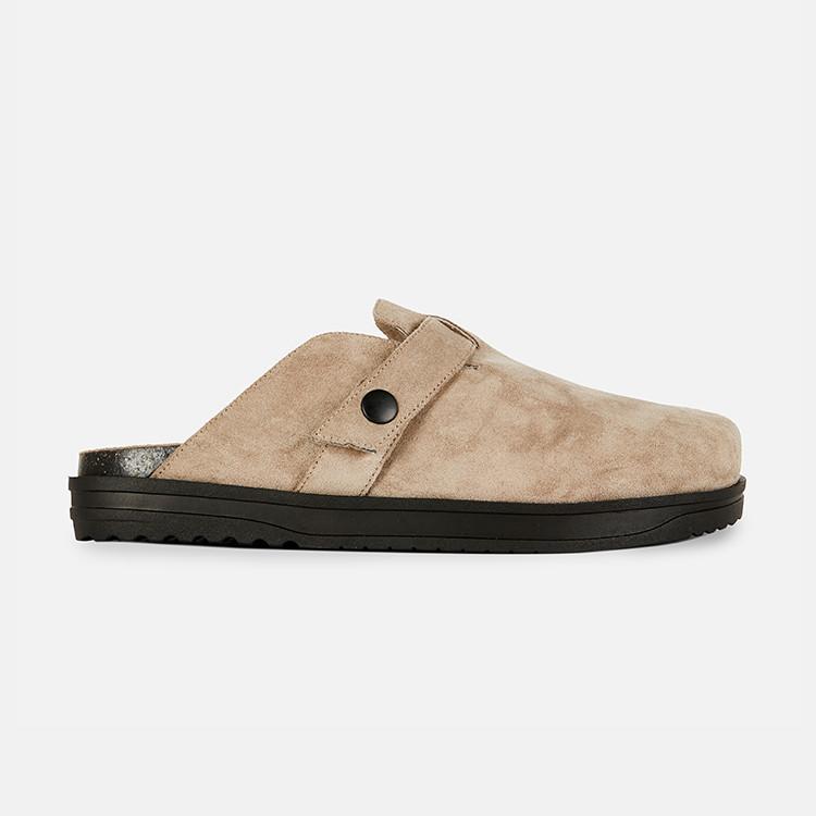 Beige suede slip-on clog with black sole and button detail on the upper strap.