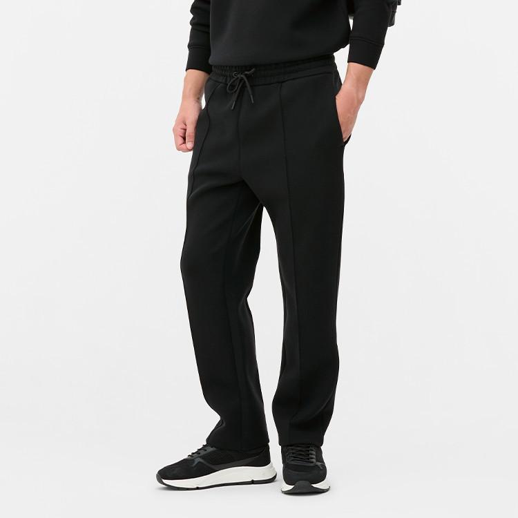 Black jogger trousers with drawstring waist and side pockets, worn with matching sweatshirt and trainers.