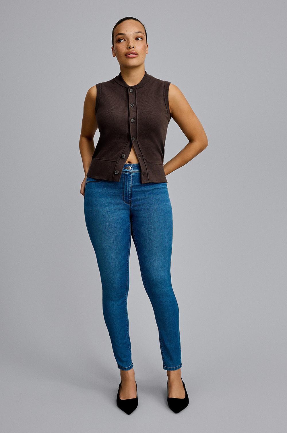 Model wearing a brown vest top with blue skinny jeans and brown heels