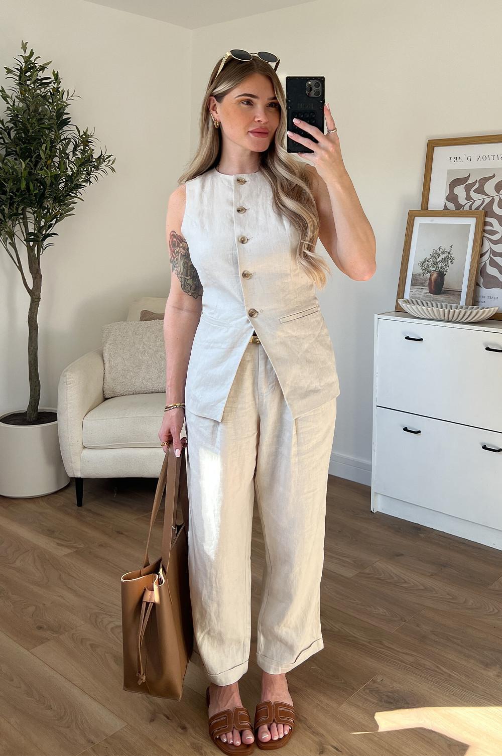 Model wearing cream linen waistcoat with matching cream linen trousers. Paired with a brown sandals, brown bag and sunglasses.