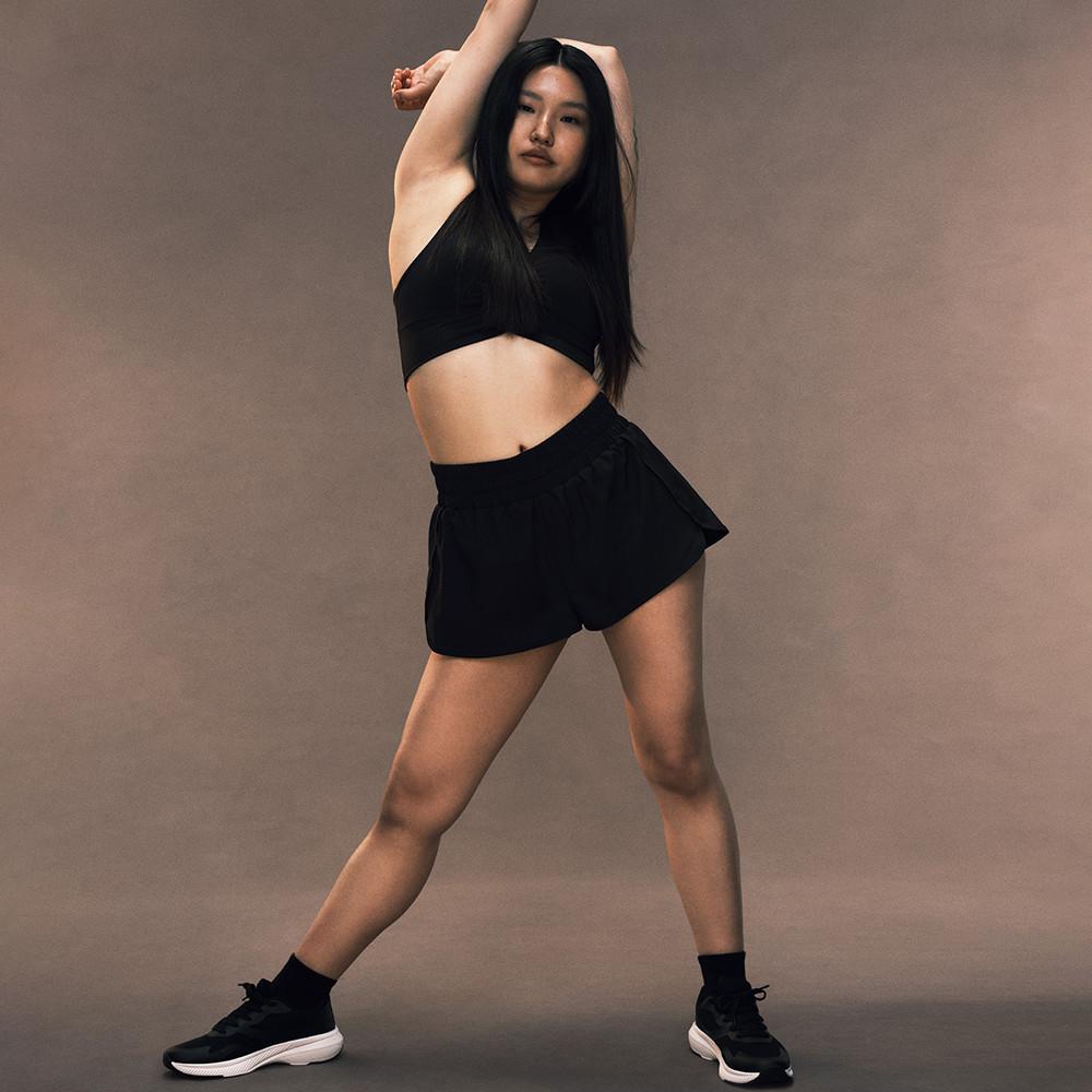 Persona che indossa un top corto sportivo nero e pantaloncini con scarpe da ginnastica nere in una posa di danza.