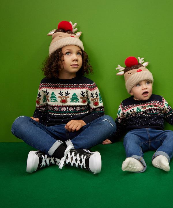 Otroka v ujemajočih se božičnih puloverjih