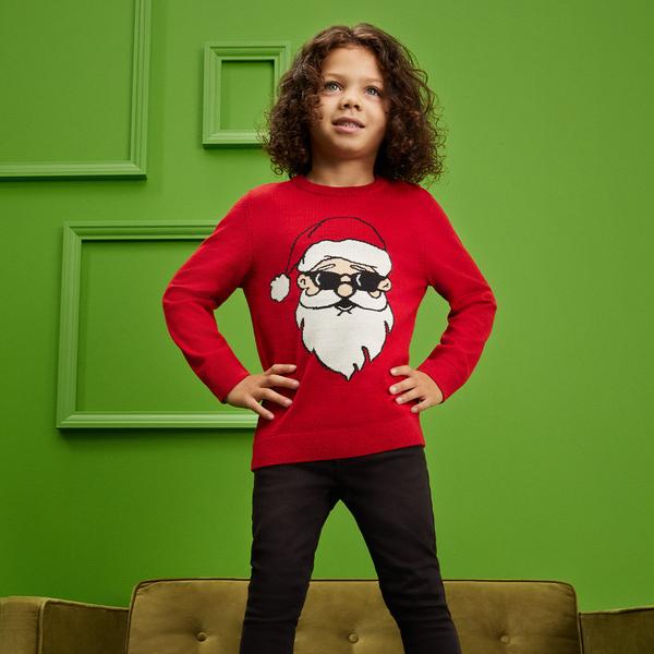 Enfant qui porte un pull rouge à motif père Noël