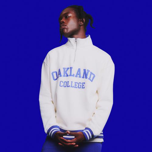 Model in white/blue slogan quarter zip sweatshirt