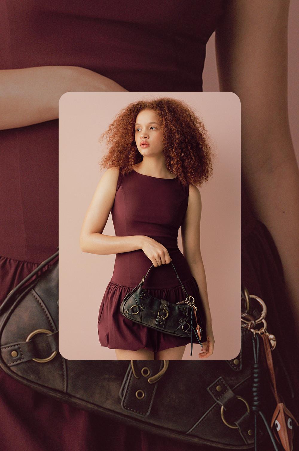 Modella che indossa un miniabito bordeaux con una borsa nera