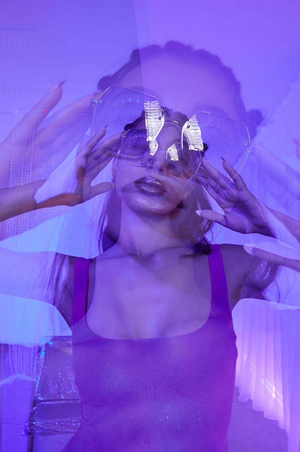 Model in oversized sunglasses, purple corset top, matching skirt, sunglasses
