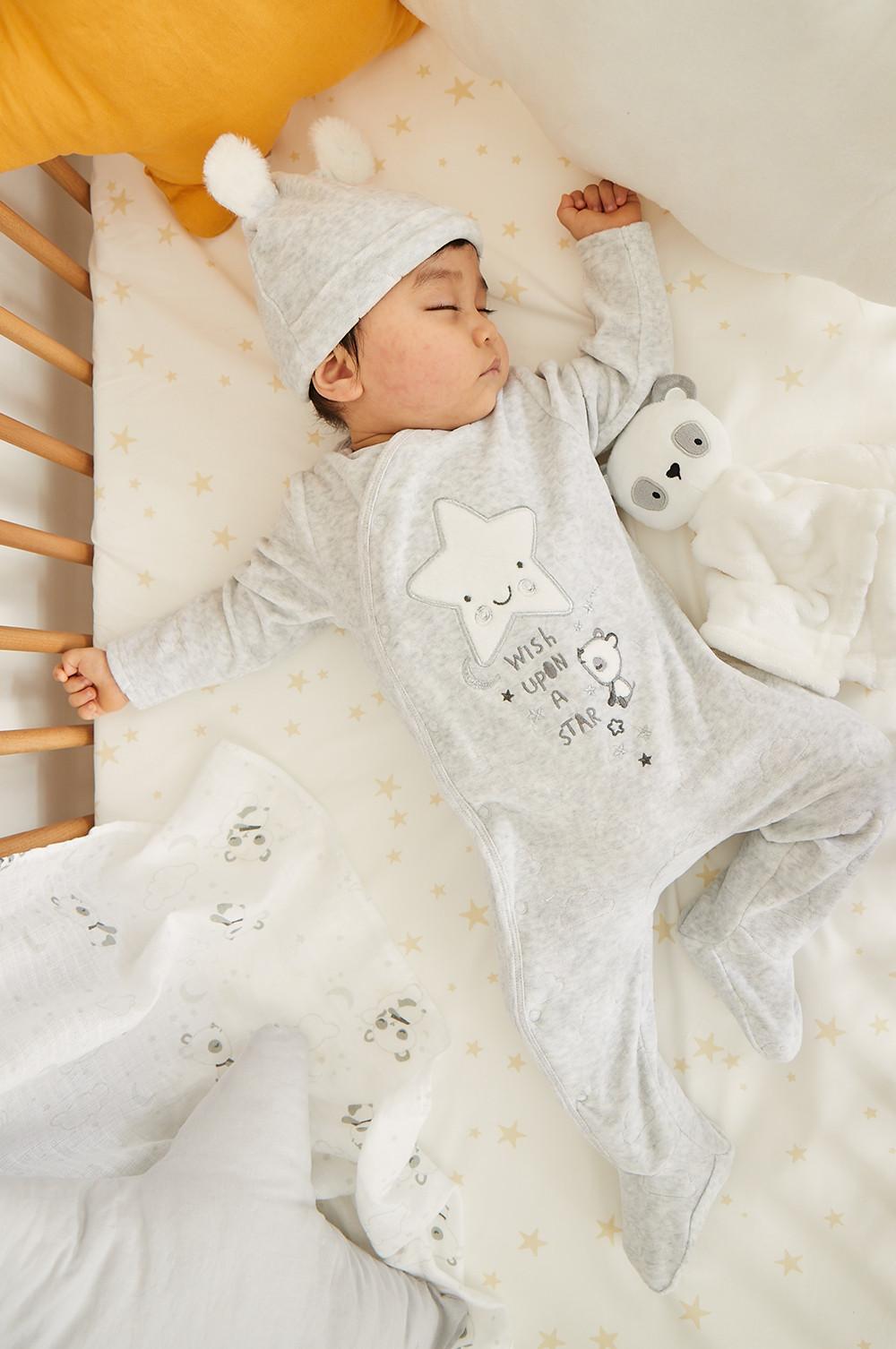 Baby in Strampler mit Sternen-Print und Mütze