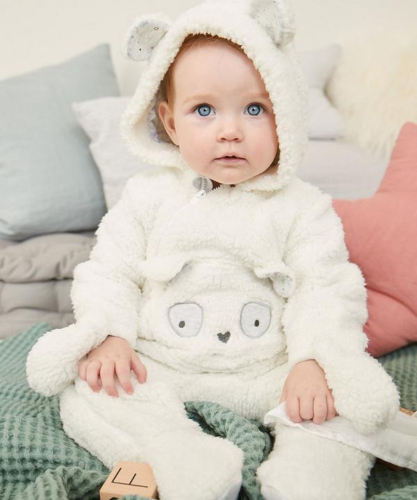 Bebé em pijama de peça única branco com urso