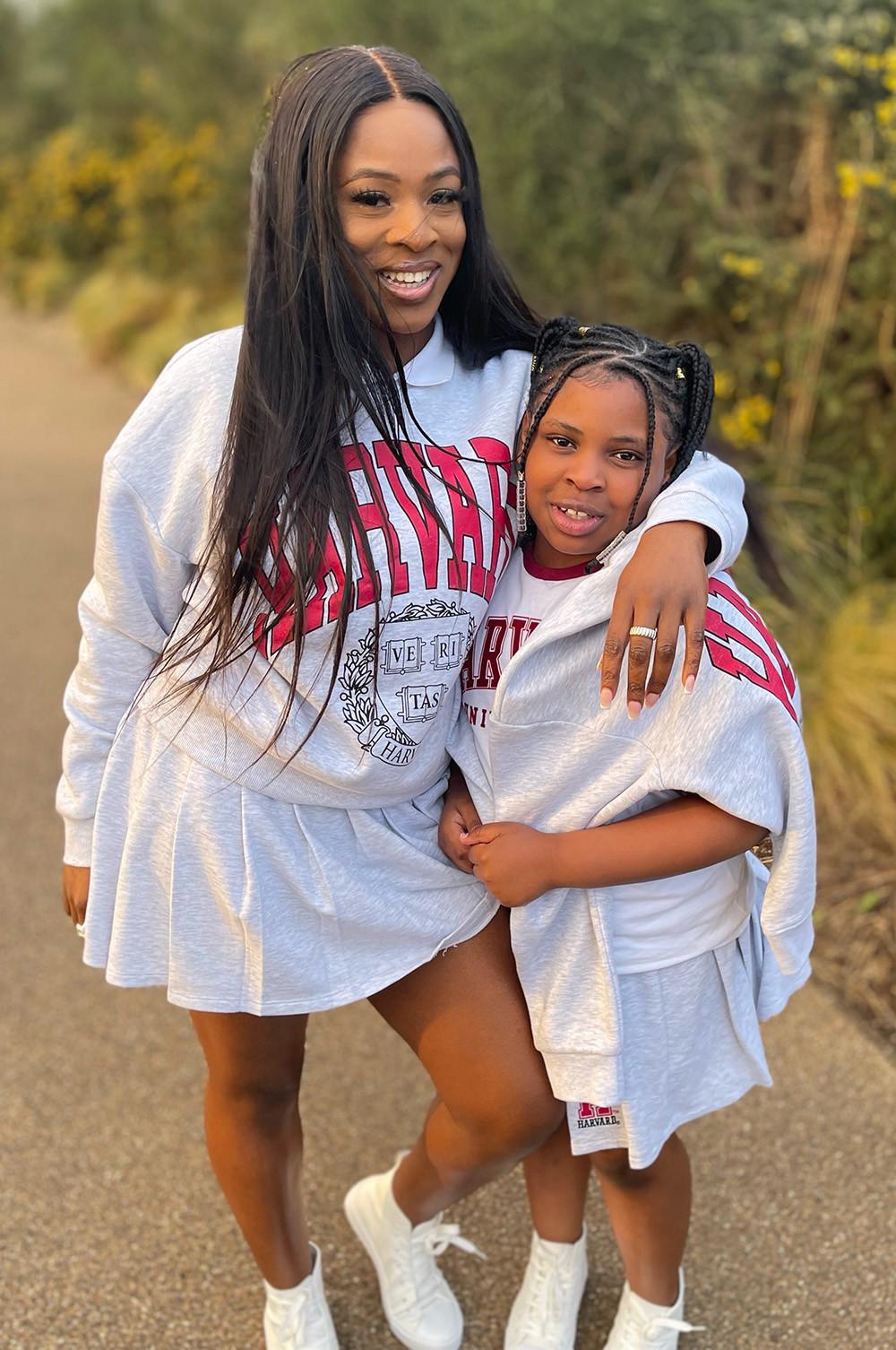 Mother and Daughter wear grey Harvard sweatshirts and tennis skirts