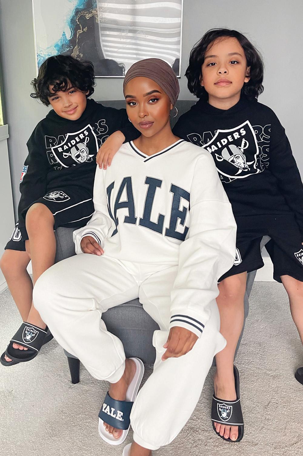 Mother wears white Yale tracksuit, while kids wear navy Raiders sweatshirt and shorts
