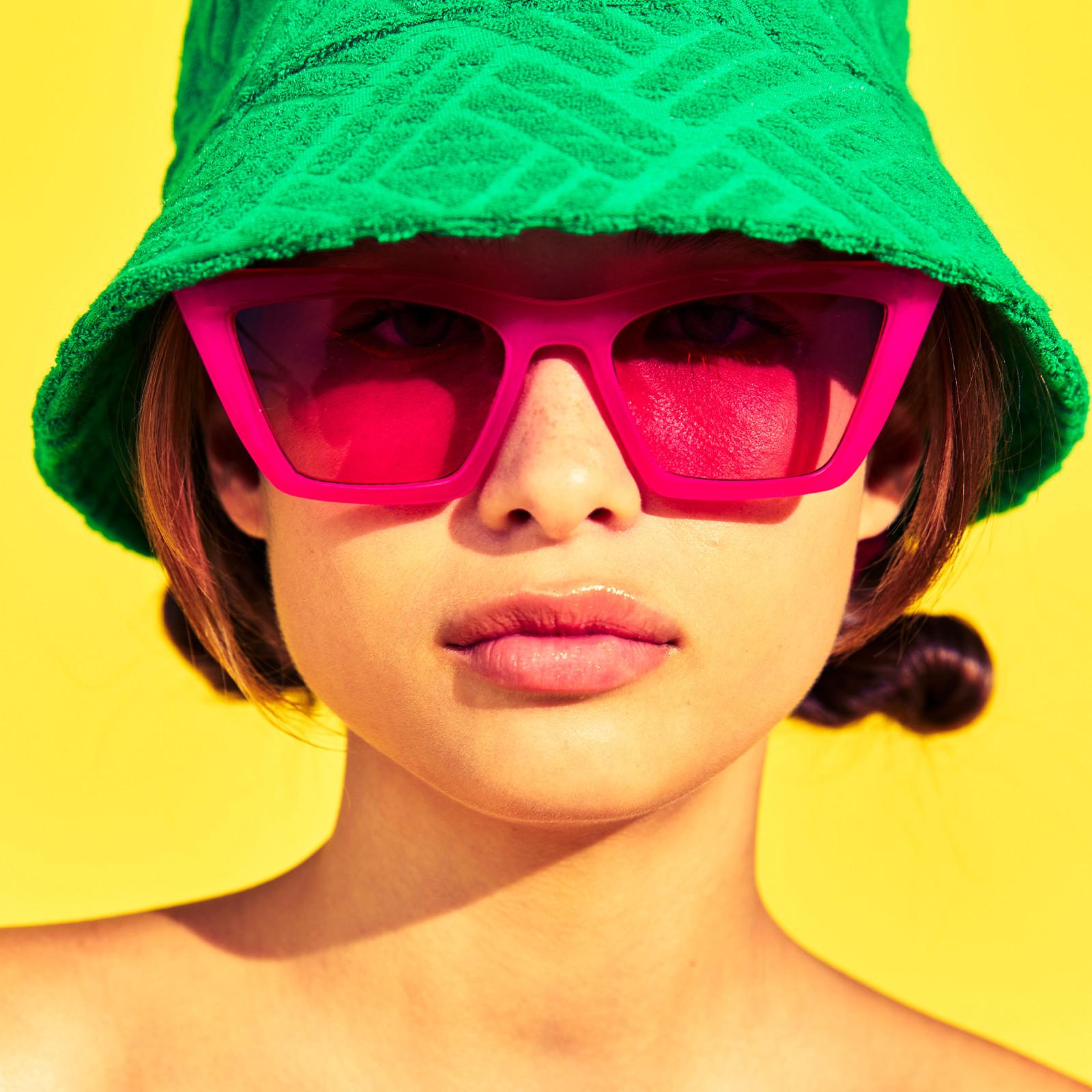 Modelo con gorro de pescador verde y gafas de sol rosas