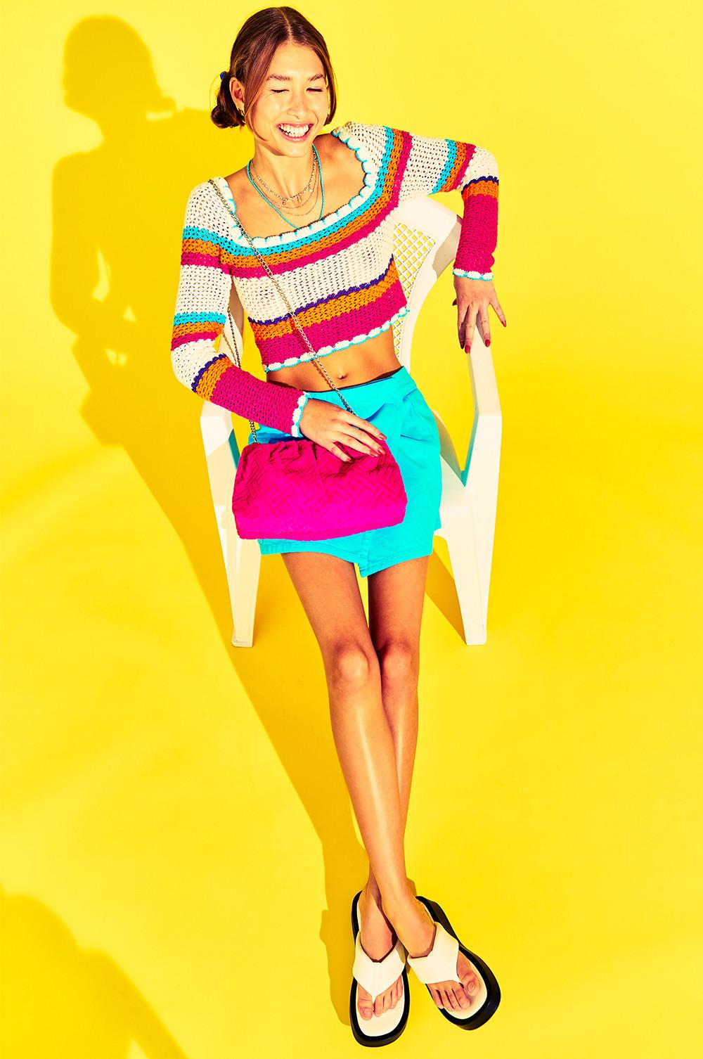 model wears crochet top, silk mini skirt and pink bag