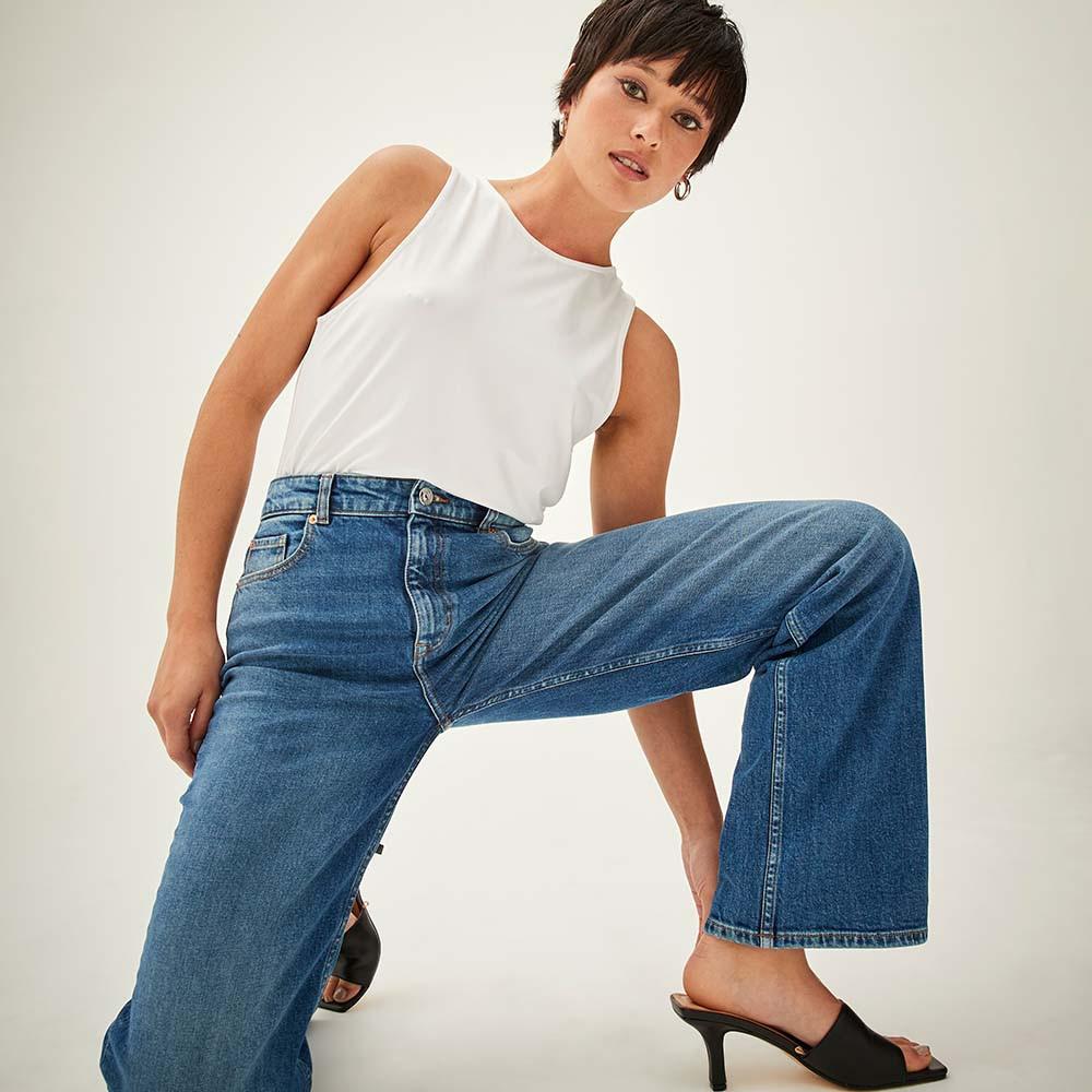 Model wears blue wide leg jeans with white top