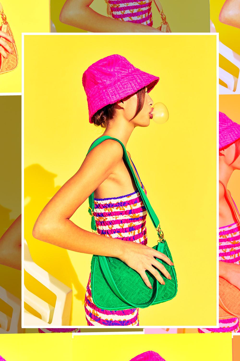 Model wears striped mini dress, green towelling bag and pink bucket hat