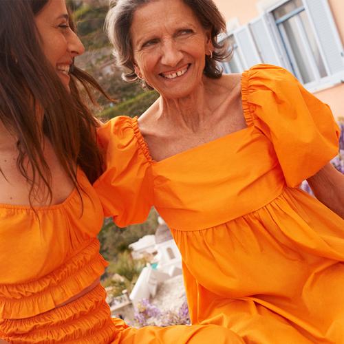 Dwie kobiety w pomarańczowej sukience z falbaną i pomarańczowym komplecie
