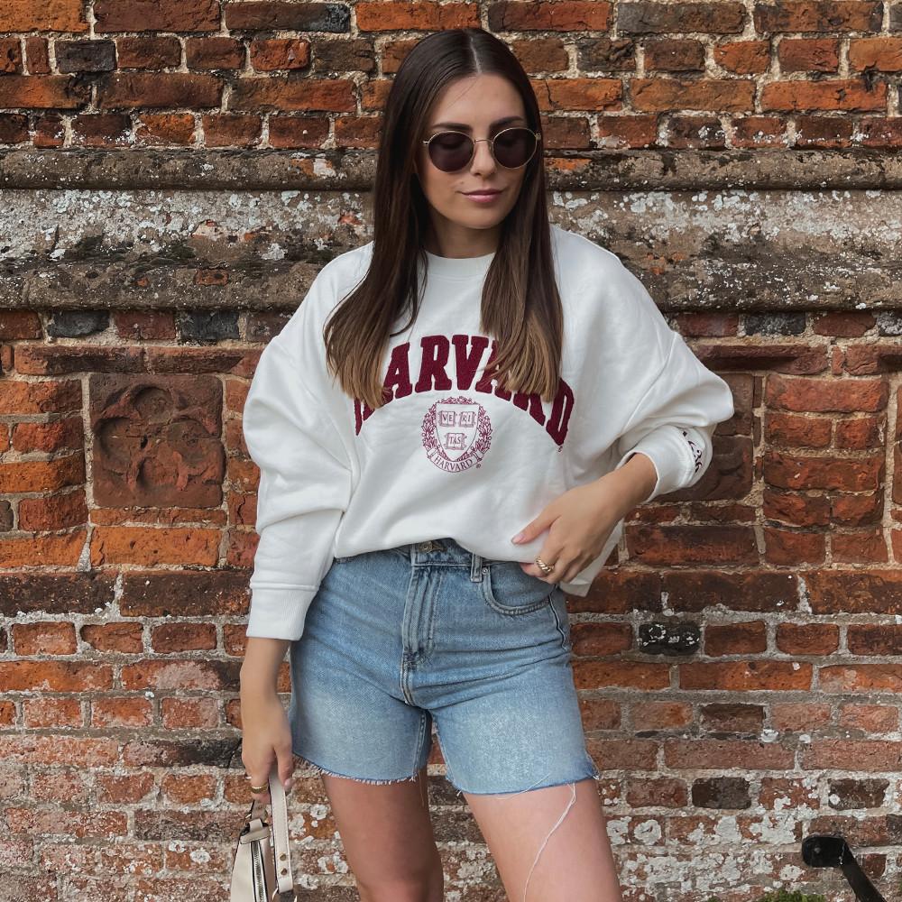 Model wearing Harvard sweatshirt and denim shorts