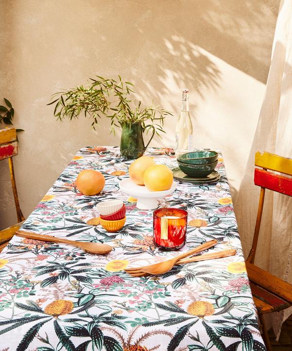 Disposición de mesa de jardín con mantel estampado, cucharas y cristalería