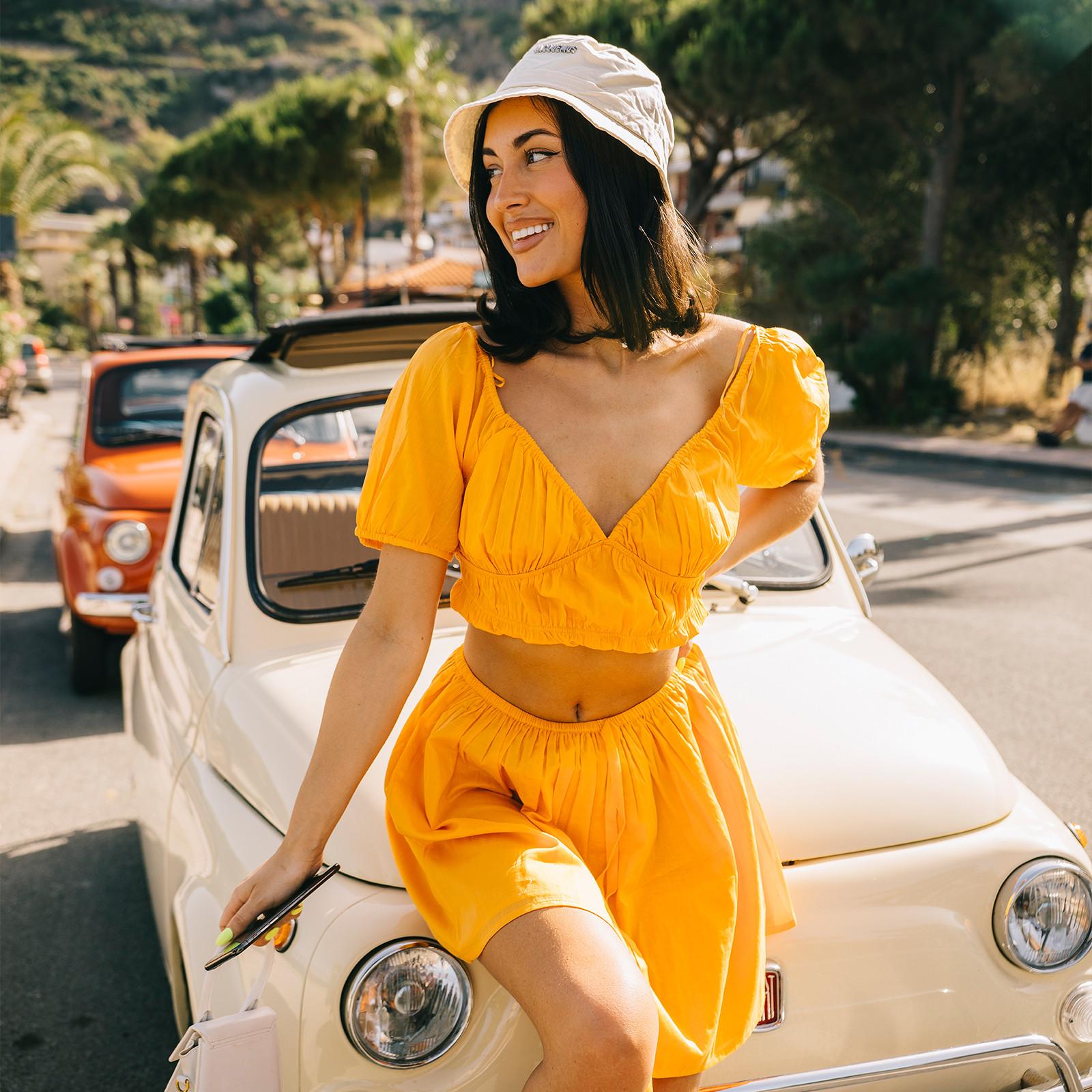 Model wears orange coord skirt and top