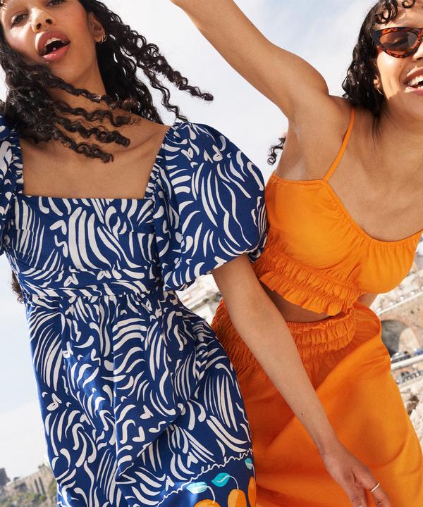 Duas mulheres com vestido azul e conjunto coordenado cor de laranja