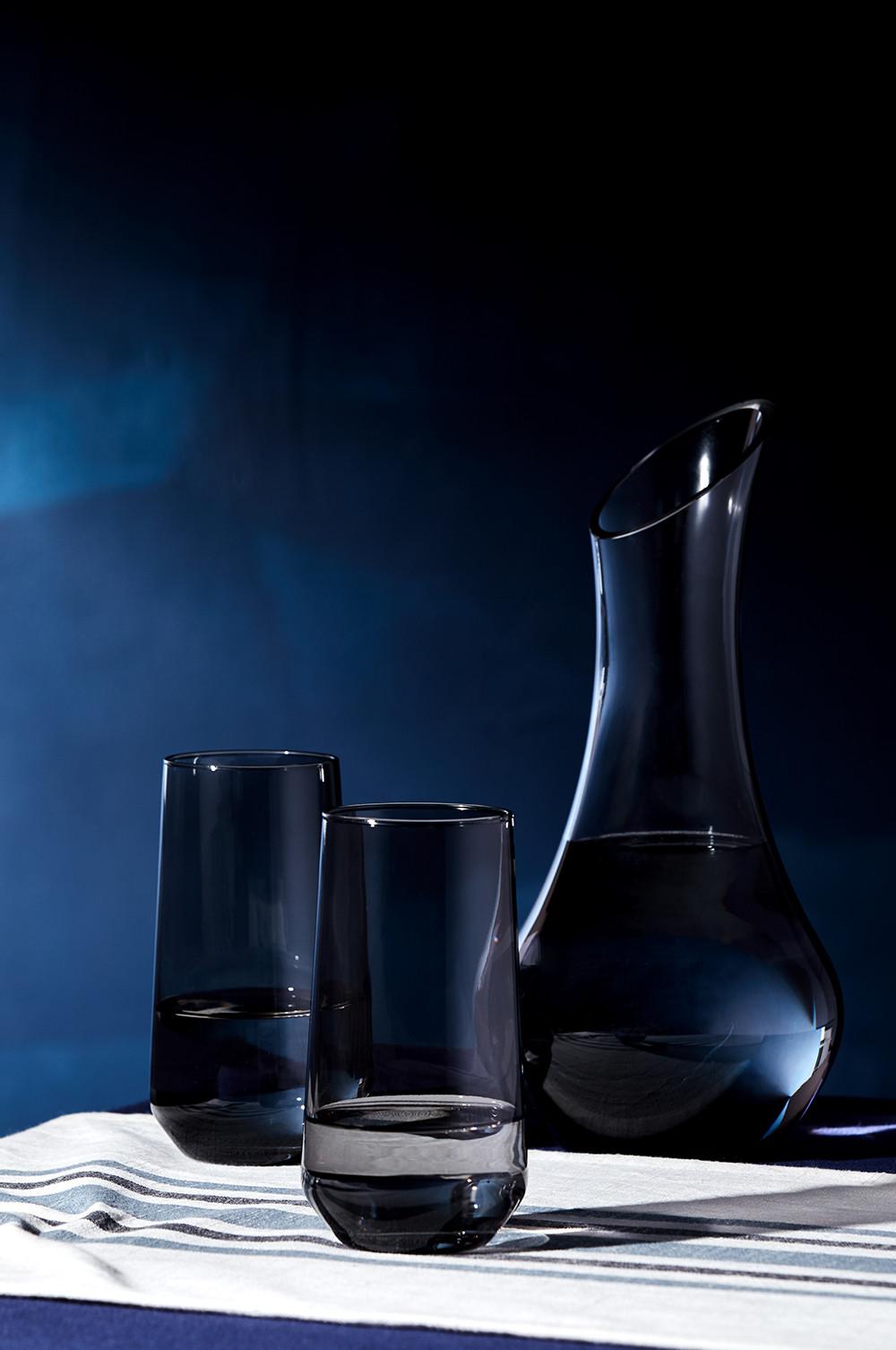 Gläser und Krug aus Rauchglas vor blauem Hintergrund