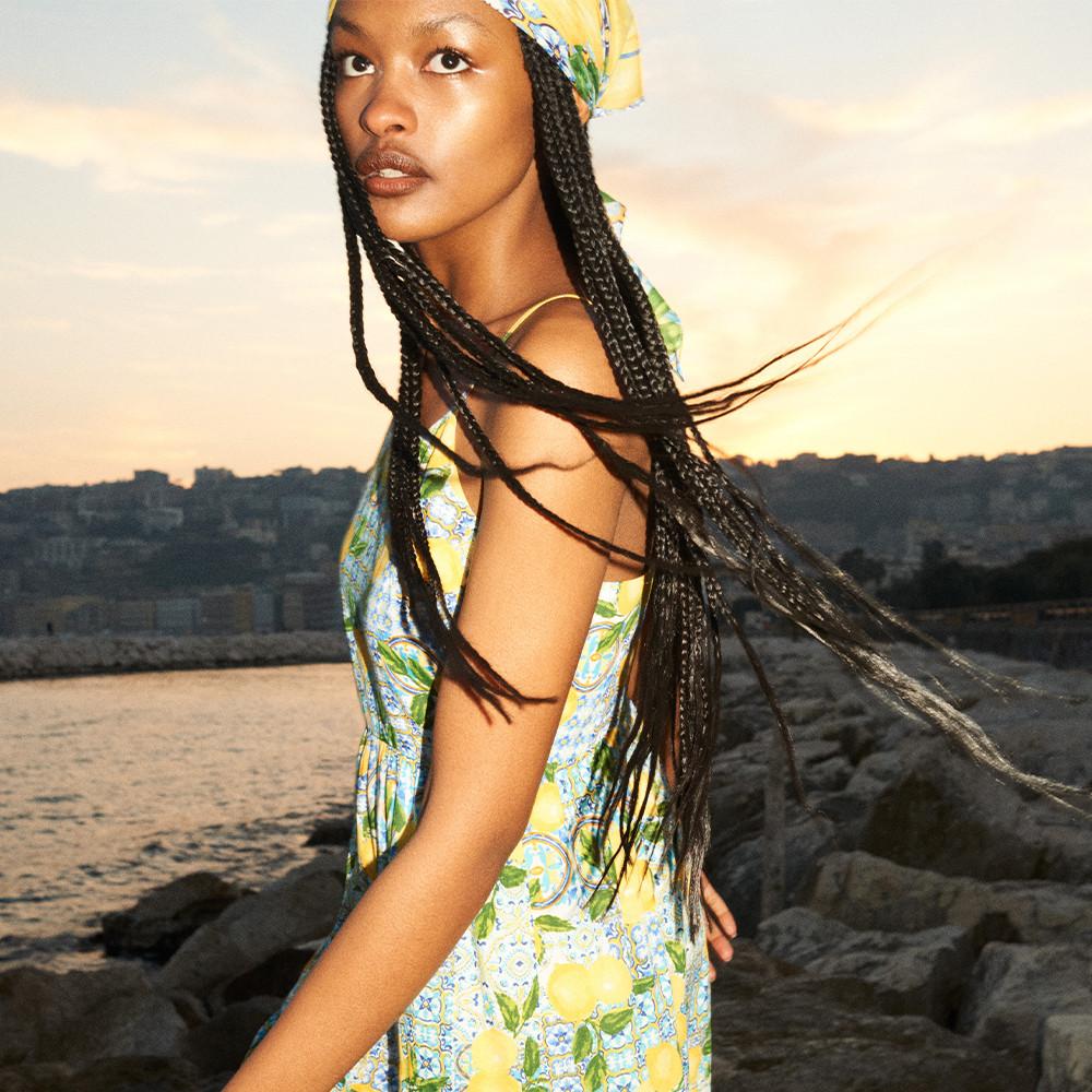 Model wears lemon print dress with coordinating headscarf