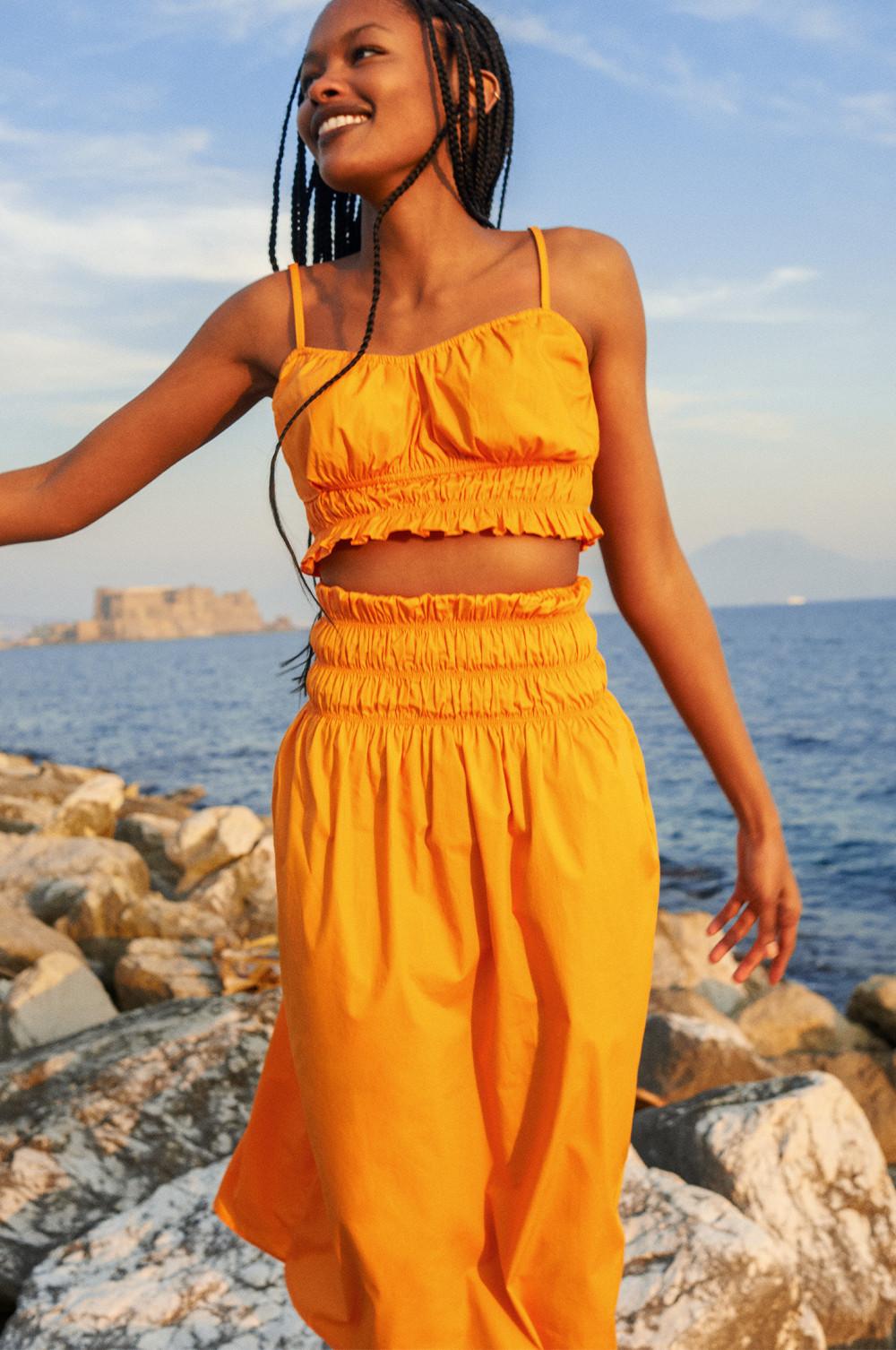 Woman wearing an orange skirt and top co-ord