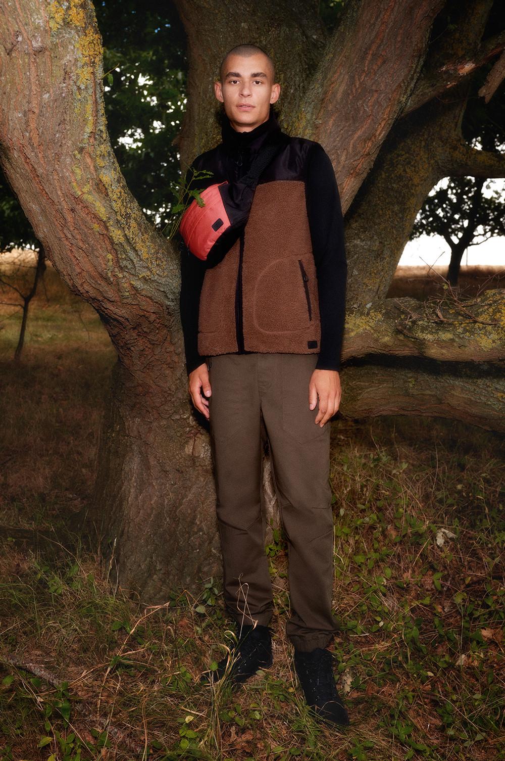 model wears brown and black fleece with cargo trousers