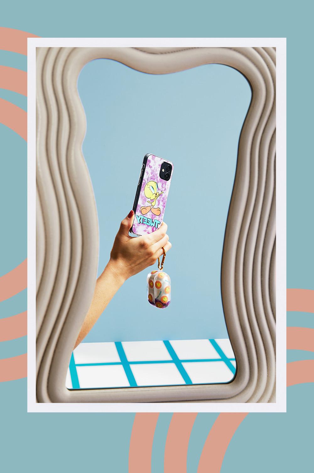 Model hält Handy mit Handy- und Kopfhörerhülle im Tweety-Look