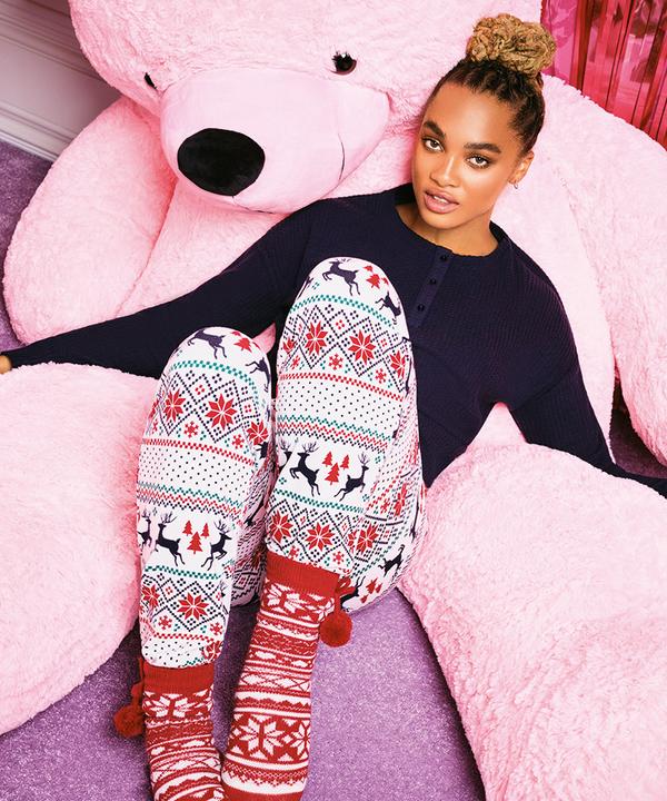 Model dat in een kerstpyjama tegen een enorme roze knuffelbeer zit