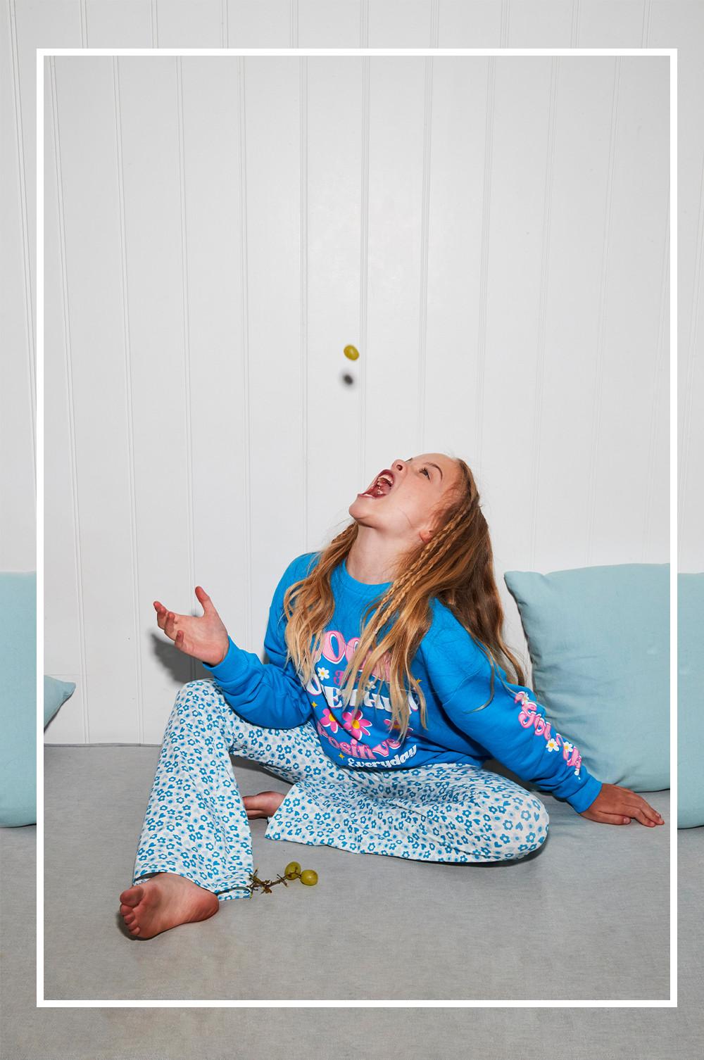 Child wears blue floral flares and blue graphic sweatshirt