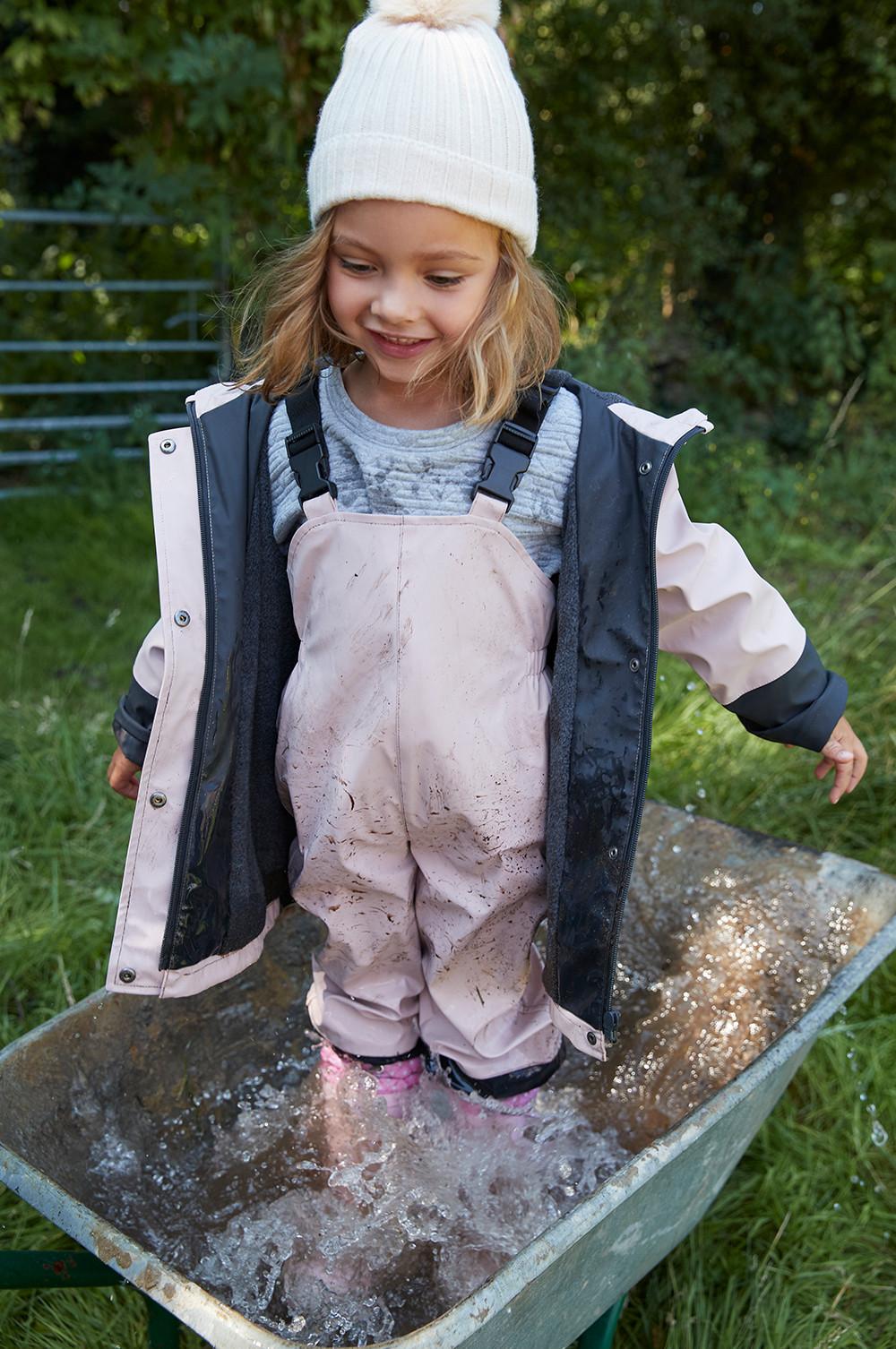 Child modelling raincoat, dungarees and rainboots