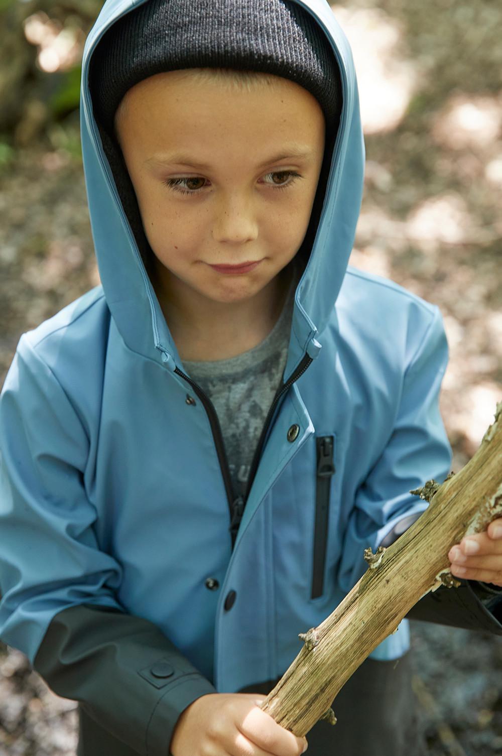 Kindermodel in blau-schwarzem Farbblock-Regenmantel