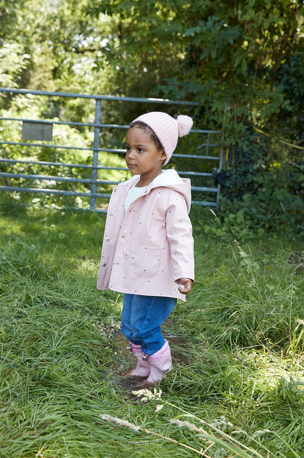 Child modelling pink polka dot raincoat