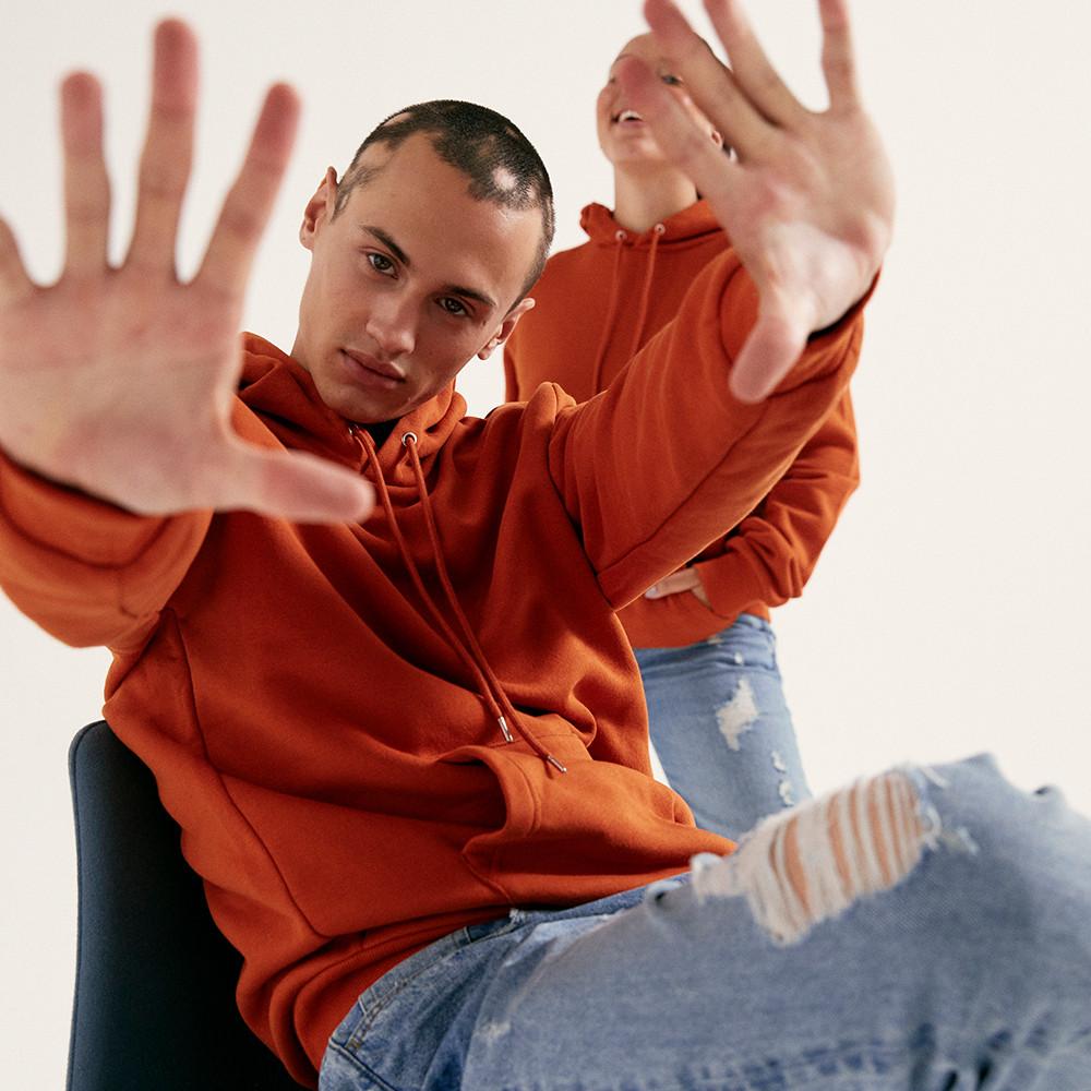 Model wearing orange hoodie and blue jeans