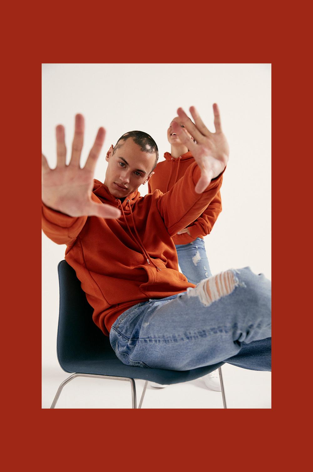 Model wearing orange hoodie and blue jeans