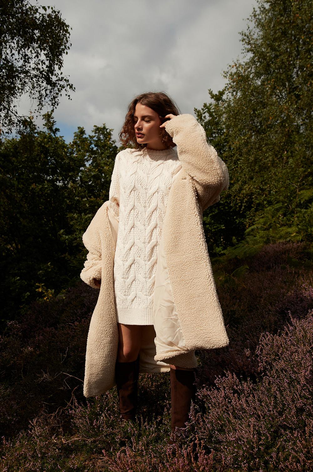 modelka v pletených šatech a kabátu z imitace ovčí kožešiny