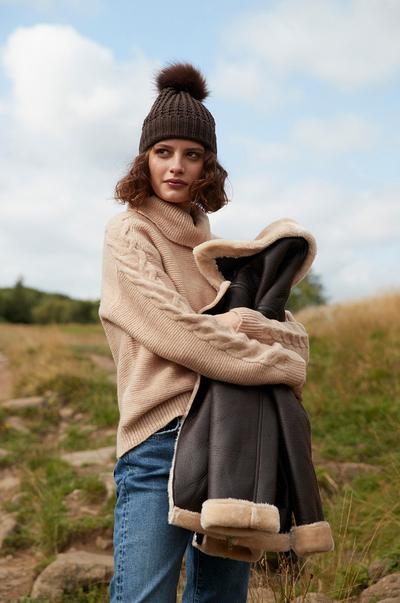 model in jumper and hat holding coat
