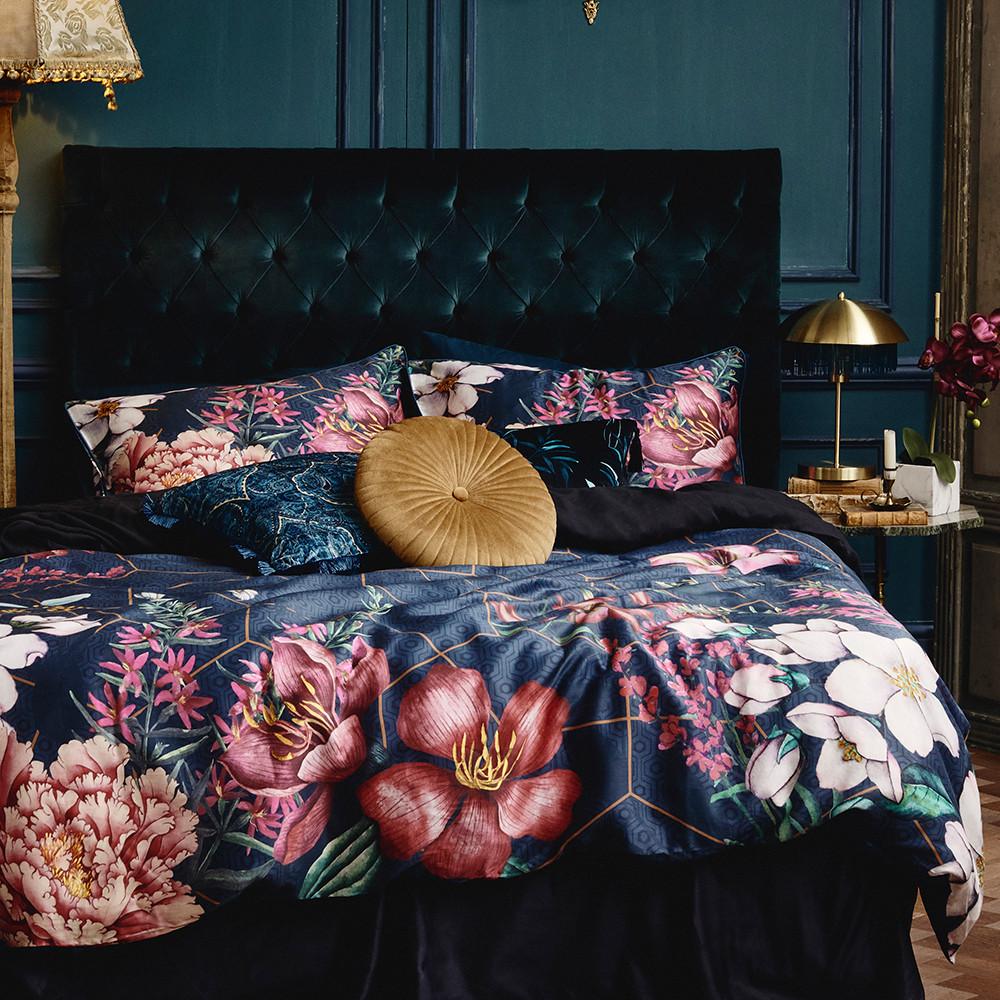 Double bed with floral bedding and velvety cushions