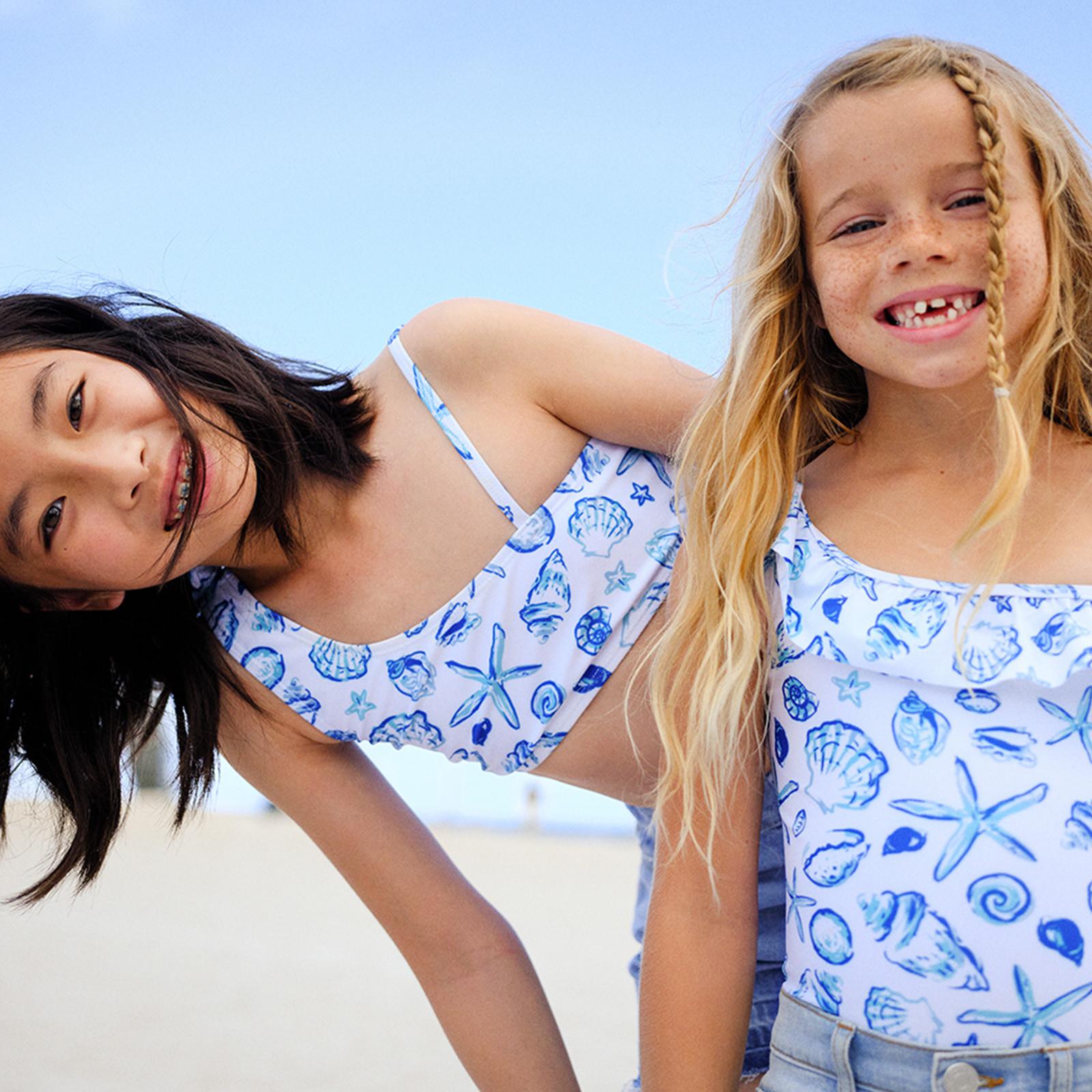 Kids wearing coordinating blue and white shell print swimwear