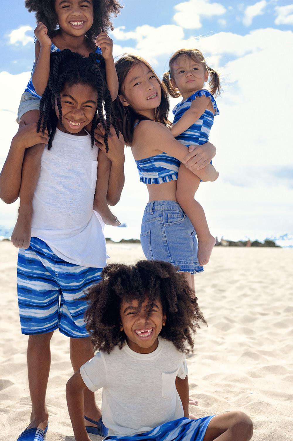 Familie in verschiedenen Badeshorts, Badeanzügen und Bikinioberteilen im Batik-Look