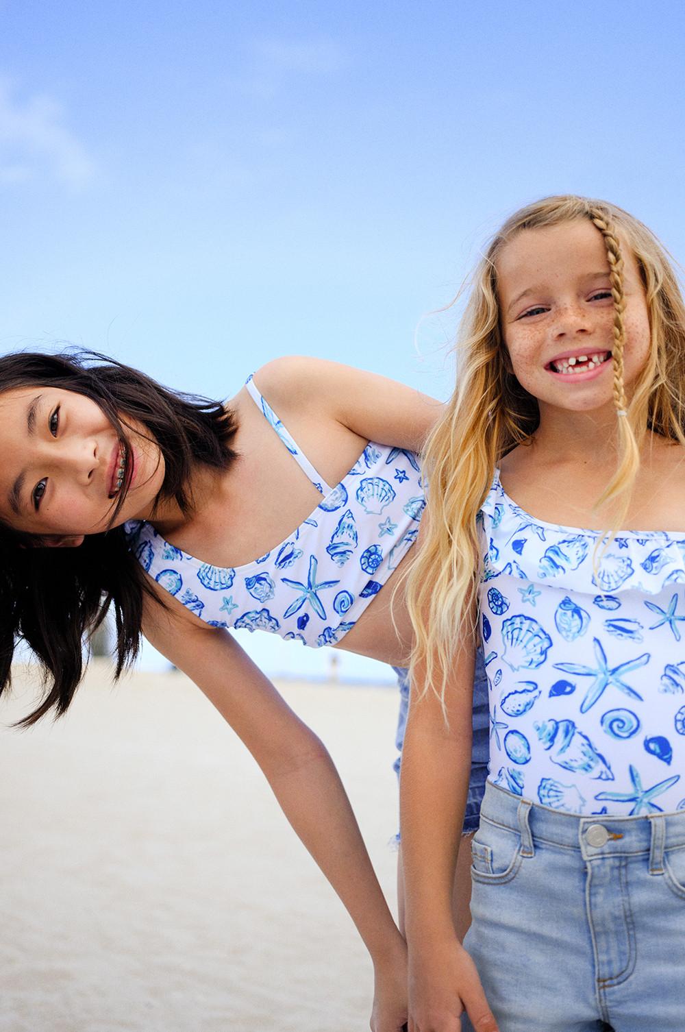 Children wearing denim shorts and patterned swim top and swimsuit