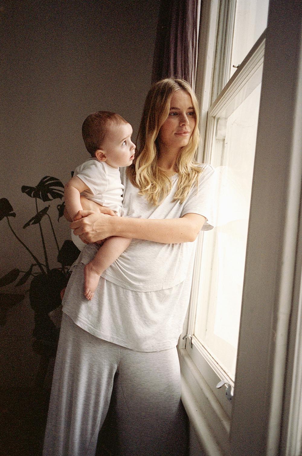 model holds baby wearing grey ribbed pyjamas