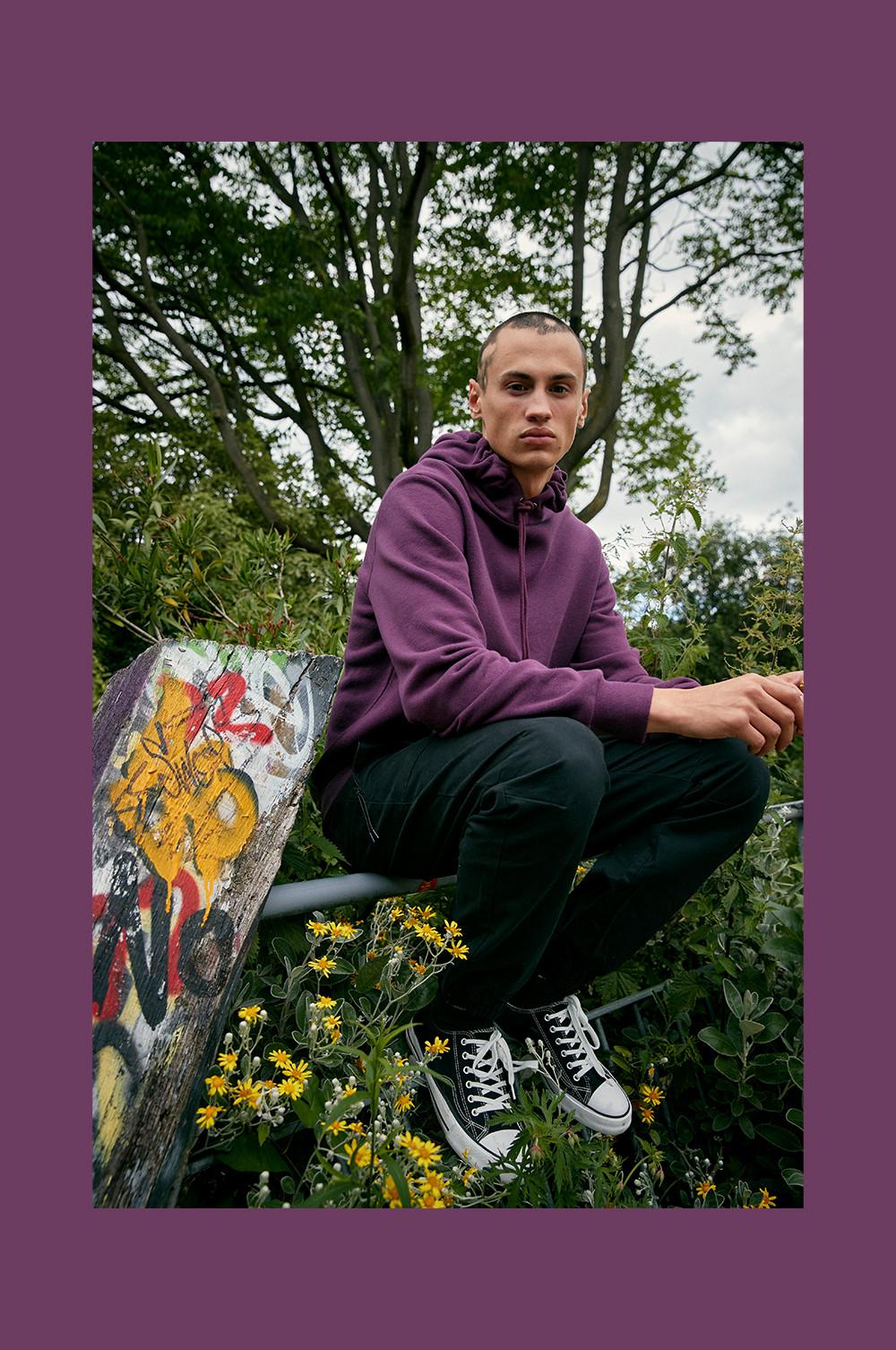 Model in violettem Kapuzenpullover und schwarzer Cargohose