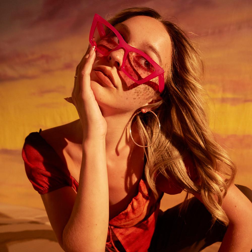 Model wears red silk top with coordinating sunglasses