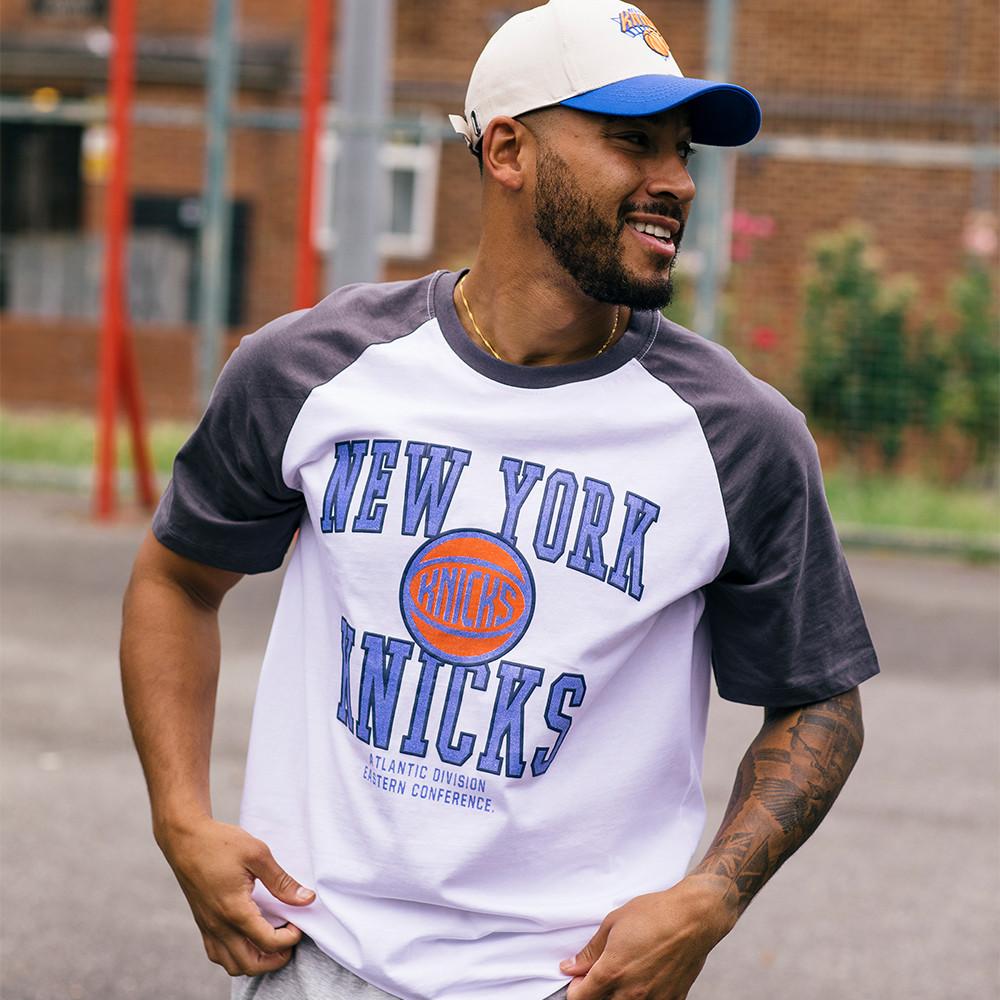 Josh Denzel porte un T-shirt et une casquette New York Knicks