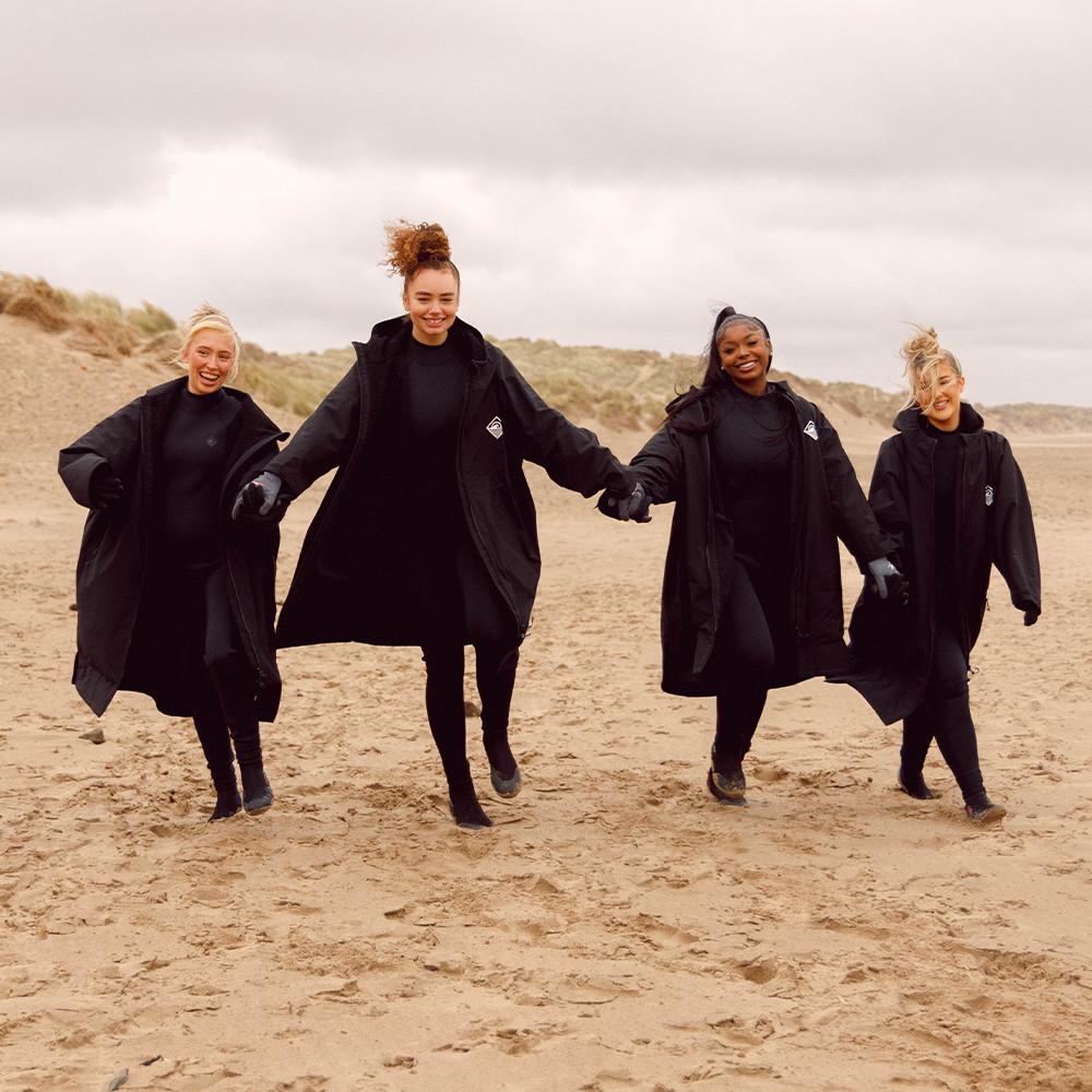 Models in black changing robes on beach