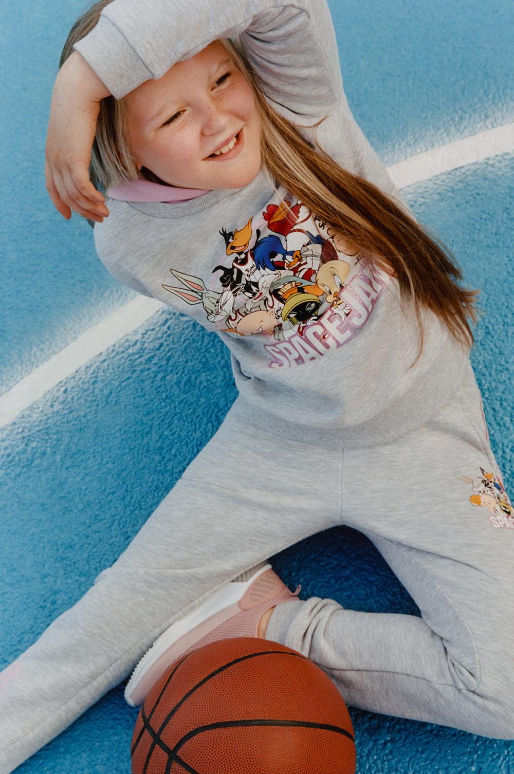 Modelo con sudadera con capucha gris y pantalones de chándal grises de «Space Jam»