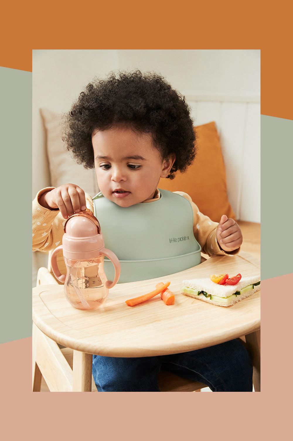 Bébé assis sur une chaise haute utilisant la ligne de tasses et bols pour bébé en silicone